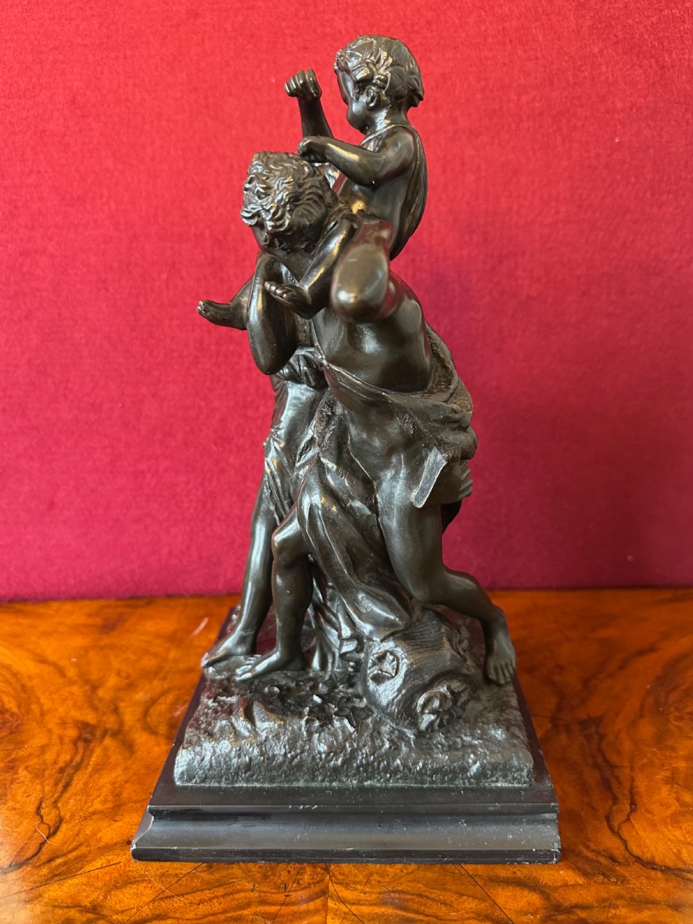 A dark patinated bronze figural sculpture depicting classical figures and putti dancing on a rectangular bronze base. View VI