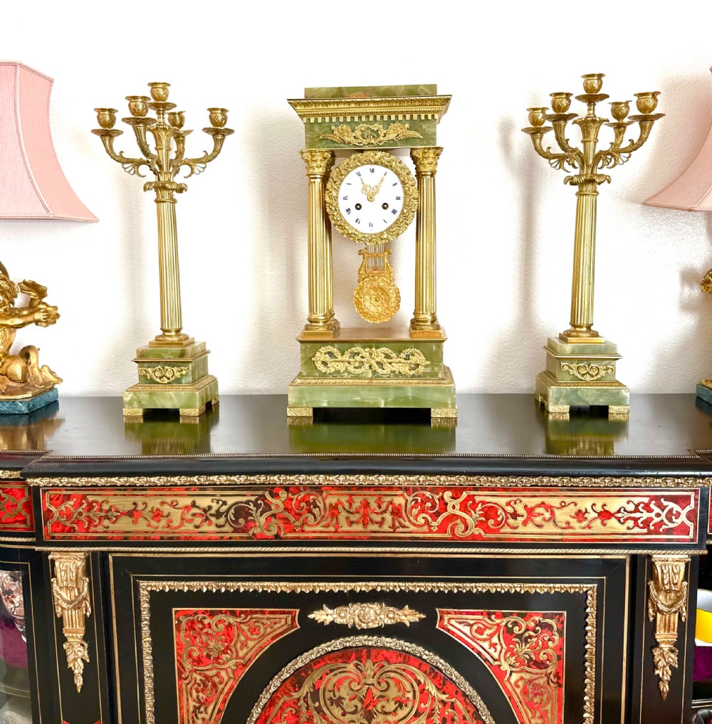 A 19th-century French clock garniture featuring a central portico-style green onyx mantel clock with gilt-bronze mounts flanked by two matching five-light candelabra. View XIII