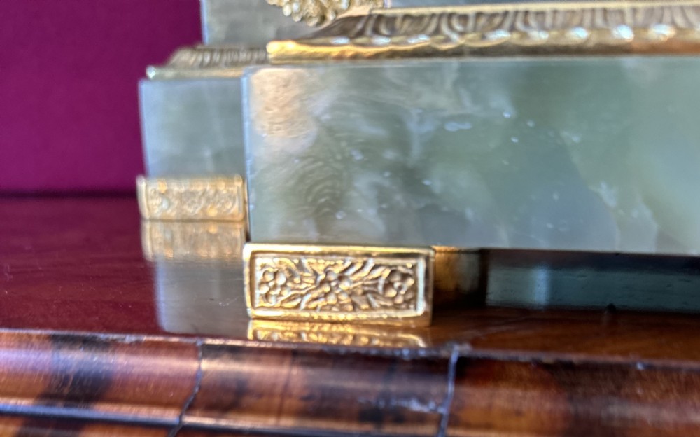A 19th-century French clock garniture featuring a central portico-style green onyx mantel clock with gilt-bronze mounts flanked by two matching five-light candelabra. View X