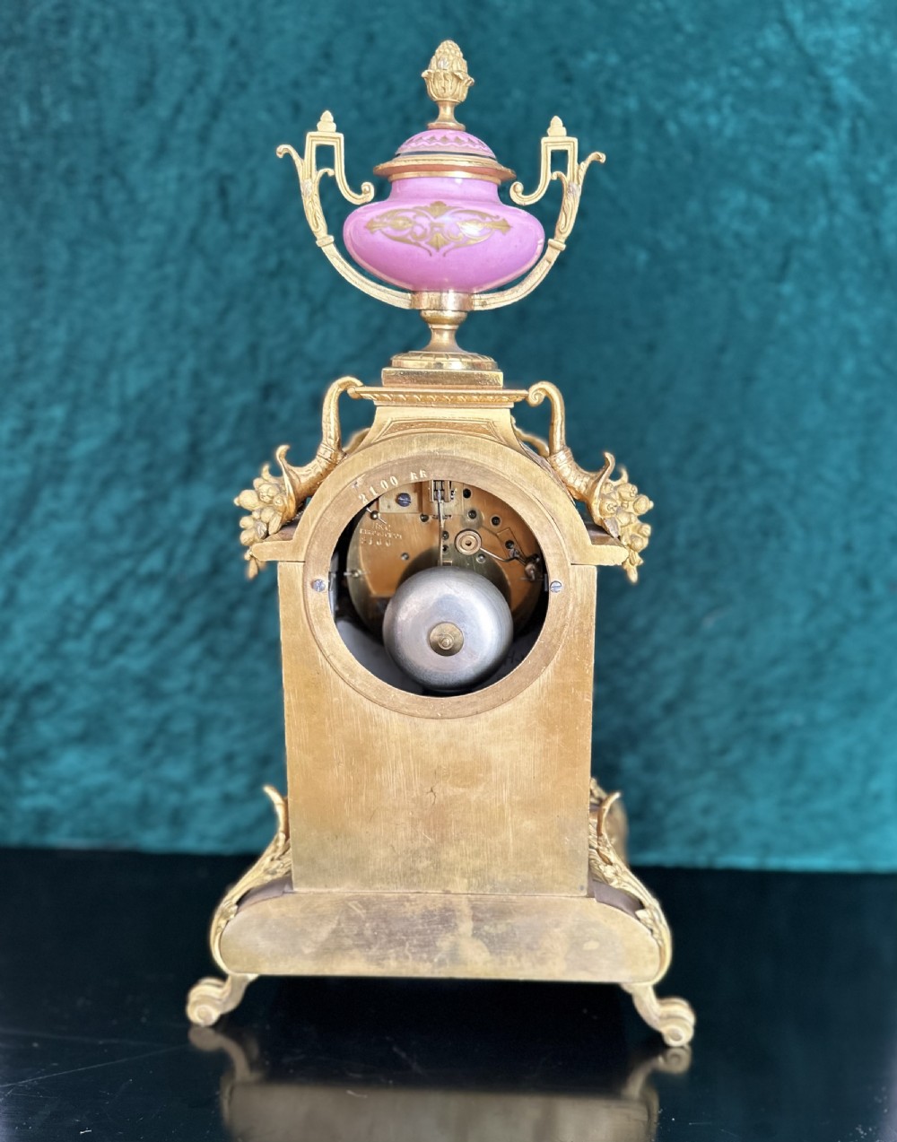 A late 19th-century French gilt bronze mantel clock featuring hand-painted pink porcelain panels, an urn finial, and an enamel dial with Roman numerals. View IX