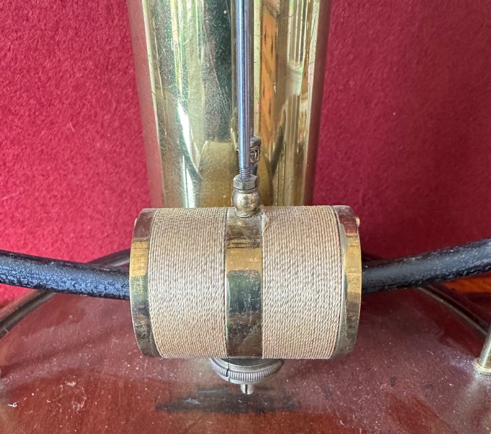 A 1920s Bulle electric clock featuring an open brass skeleton movement and white dial, encased within a clear glass dome on a dark wooden circular base. View II