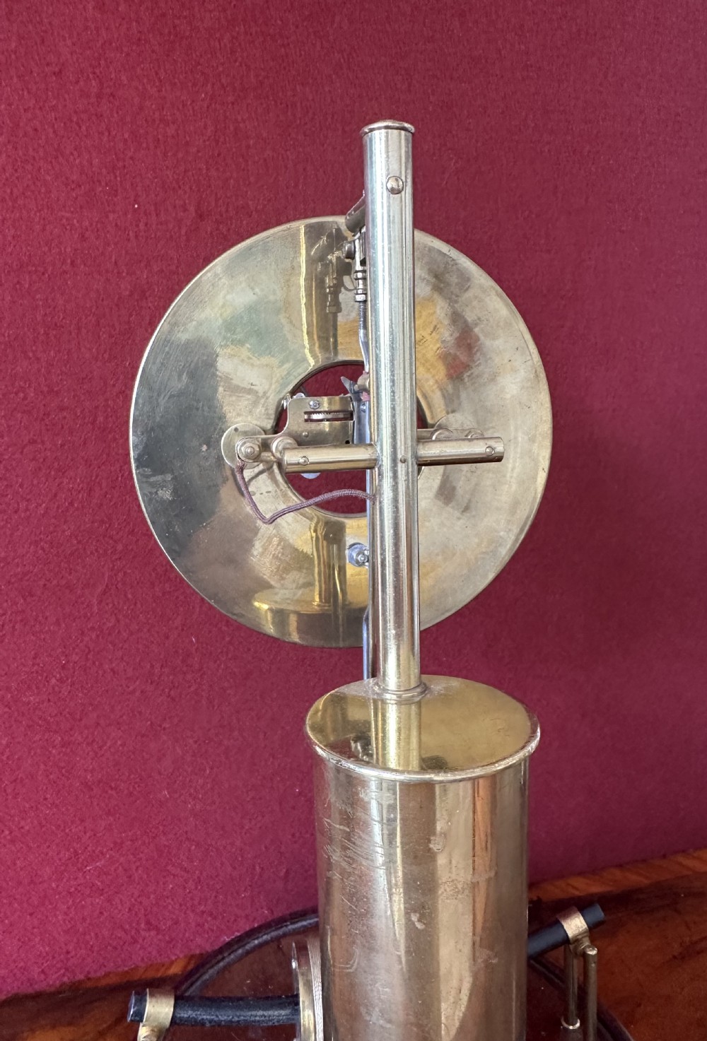 A 1920s Bulle electric clock featuring an open brass skeleton movement and white dial, encased within a clear glass dome on a dark wooden circular base. View VII