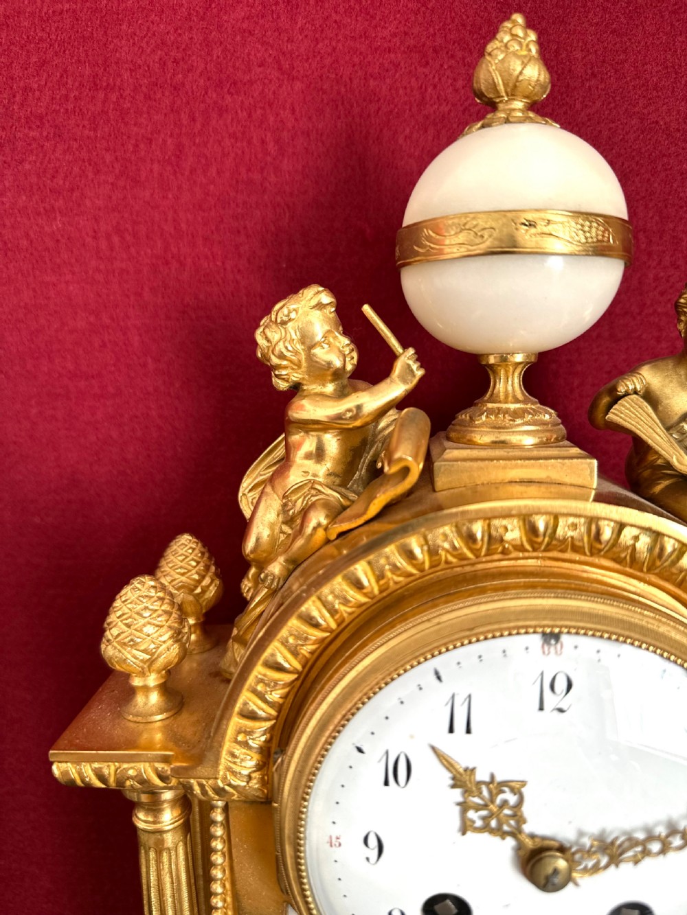 A late nineteenth-century French Louis XVI revival mantel clock made of gilt ormolu and white marble, featuring putti figures flanking a white enamel dial. View II
