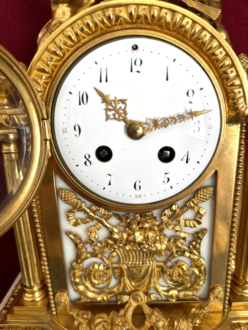 A late nineteenth-century French Louis XVI revival mantel clock made of gilt ormolu and white marble, featuring putti figures flanking a white enamel dial. View V
