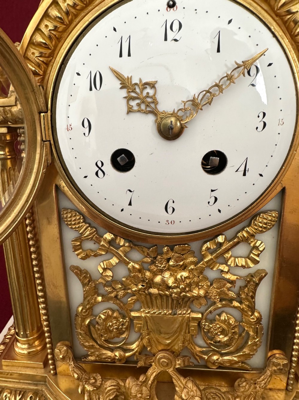 A late nineteenth-century French Louis XVI revival mantel clock made of gilt ormolu and white marble, featuring putti figures flanking a white enamel dial. View XII