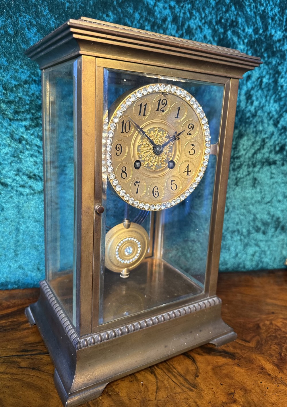 A late 19th-century gilt brass four-glass mantel clock featuring bevelled glass panels, a jewelled bezel, and a decorative circular pendulum. View III
