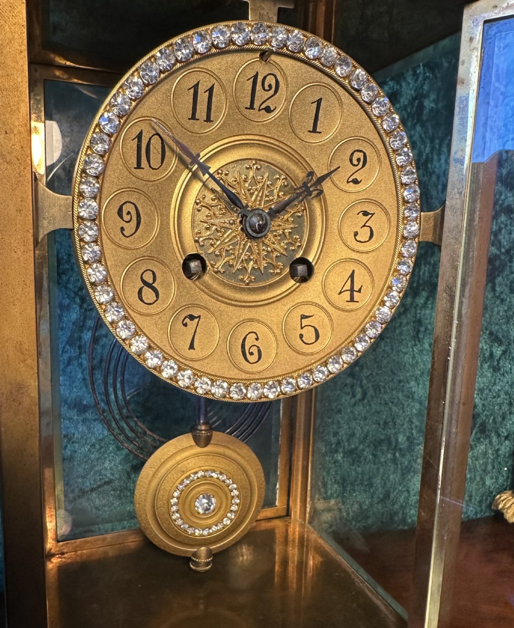 A late 19th-century gilt brass four-glass mantel clock featuring bevelled glass panels, a jewelled bezel, and a decorative circular pendulum. View IV