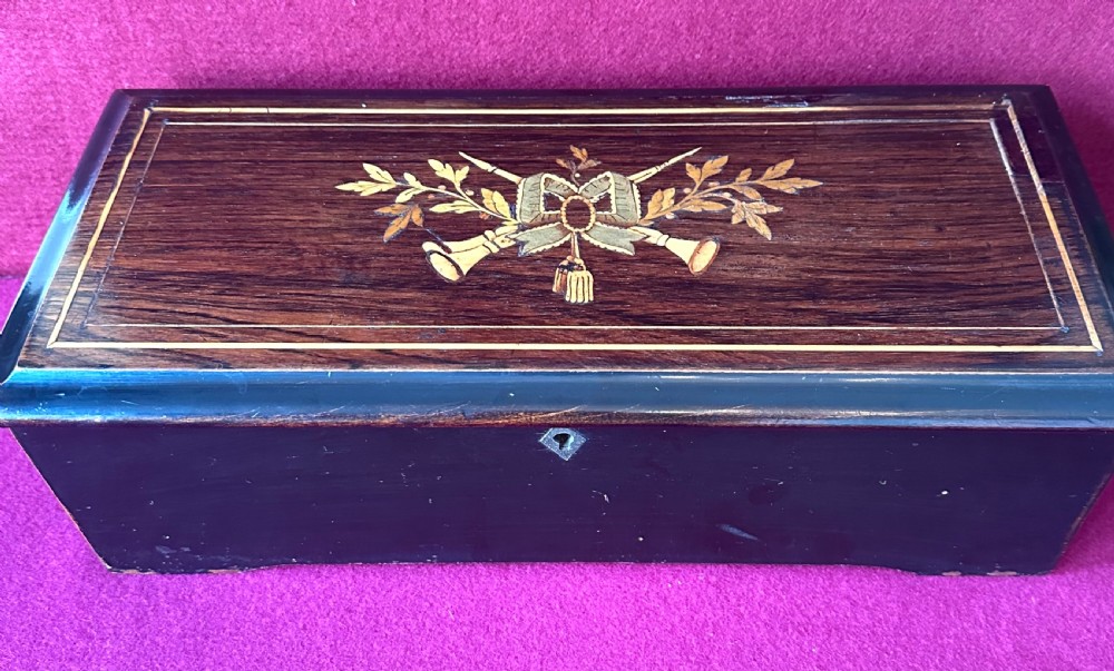 A Victorian ebonised wood music box shown with its hinged lid open, revealing a printed tune card and an internal glass cover over a brass cylinder and steel comb mechanism. View II