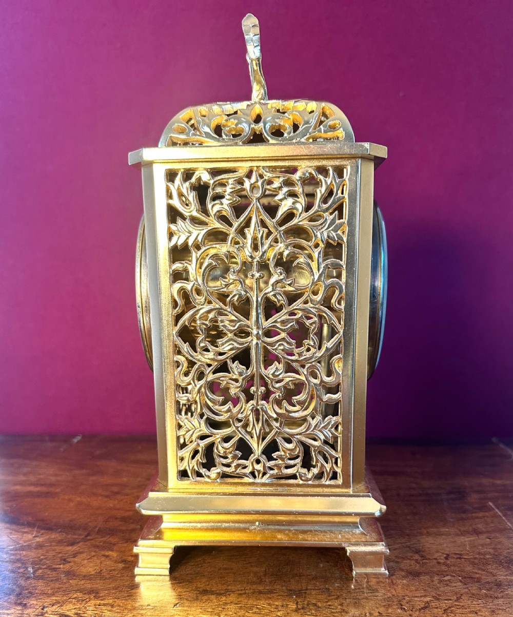 A late Victorian gilded brass mantel clock featuring intricate pierced fretwork side panels, a top carrying handle, and an engraved dial with white enamel Roman numeral markers. View II
