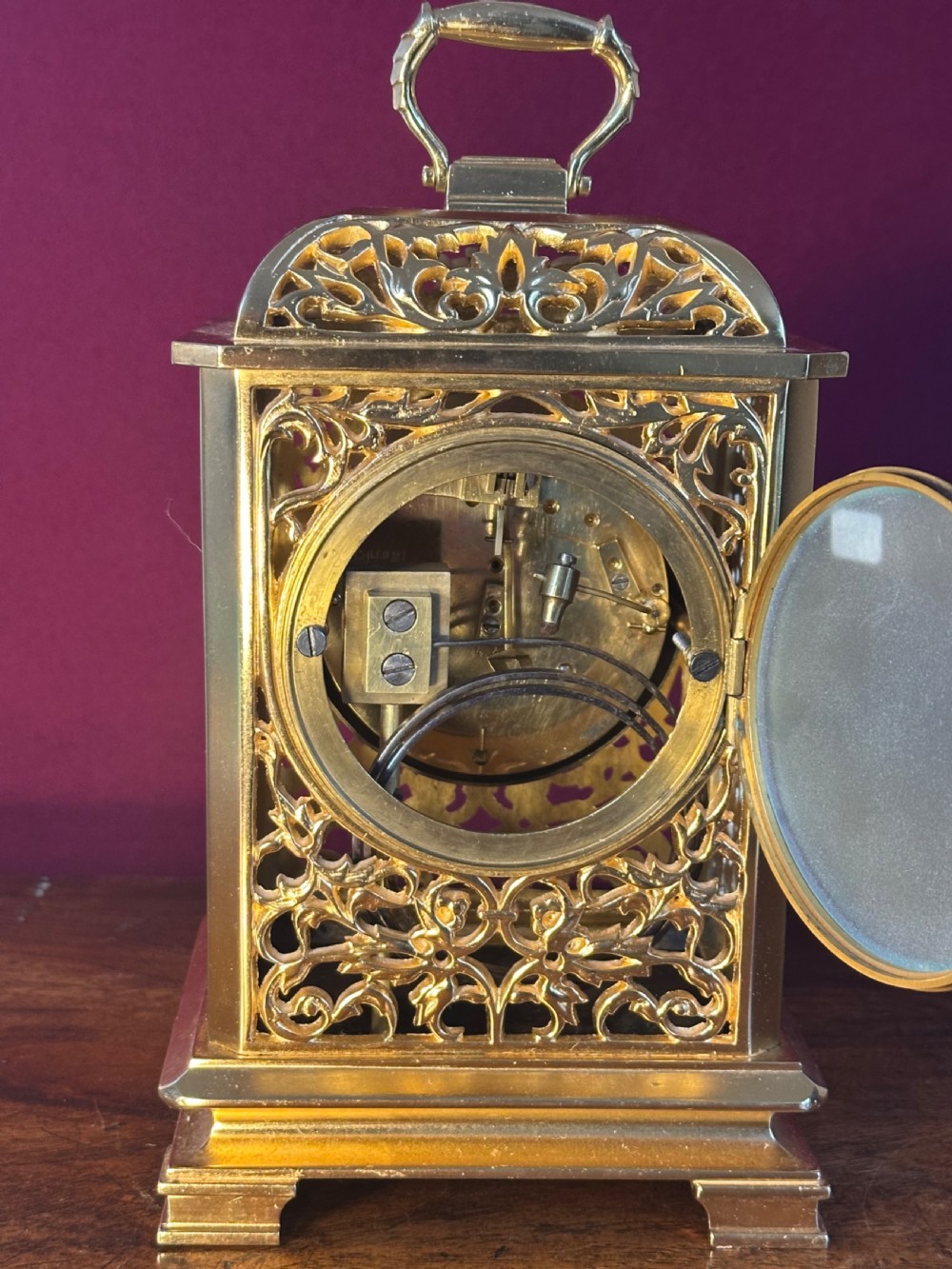A late Victorian gilded brass mantel clock featuring intricate pierced fretwork side panels, a top carrying handle, and an engraved dial with white enamel Roman numeral markers. View IV
