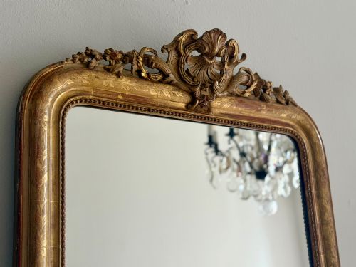fig 1. An antique French Louis Philippe giltwood mirror featuring a carved crest and incised floral frame detailing.
