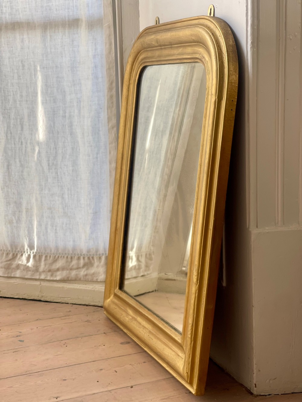 An upright antique French Louis Philippe mirror featuring an ogee-moulded frame with a gilded gold leaf finish and rounded upper corners. View VI
