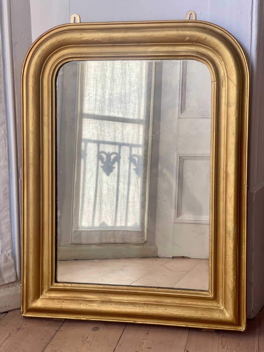 An upright antique French Louis Philippe mirror featuring an ogee-moulded frame with a gilded gold leaf finish and rounded upper corners. View VIII