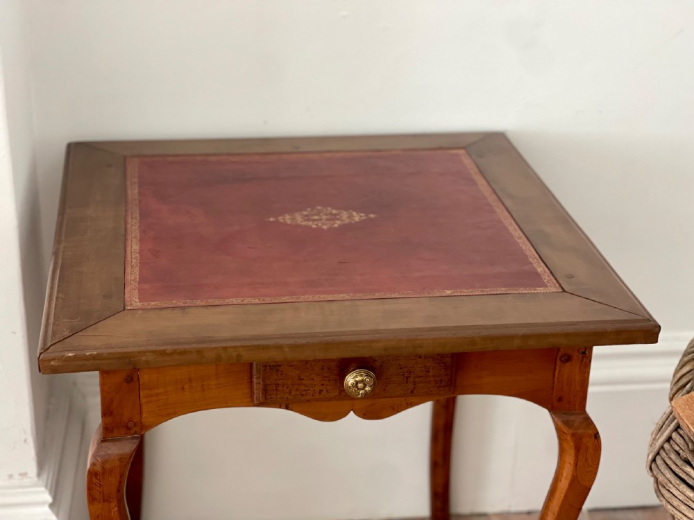 An antique French side table featuring a warm brown leather inset top, slender cabriole legs, and a single drawer with a brass knob. View II
