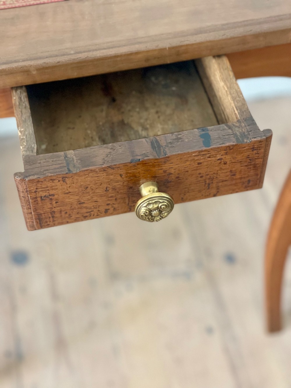 An antique French side table featuring a warm brown leather inset top, slender cabriole legs, and a single drawer with a brass knob. View V
