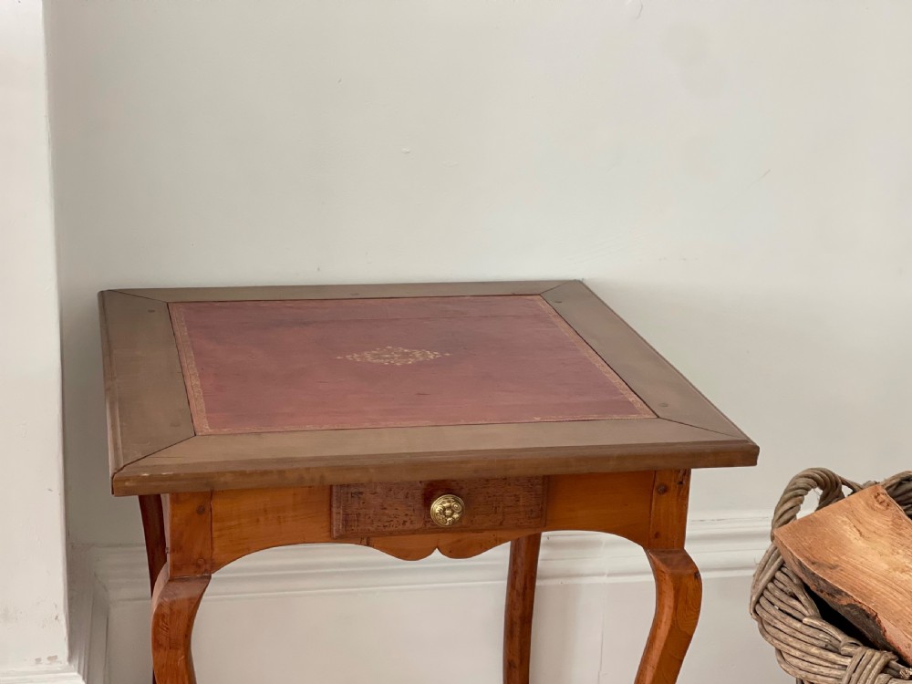 An antique French side table featuring a warm brown leather inset top, slender cabriole legs, and a single drawer with a brass knob. View VI