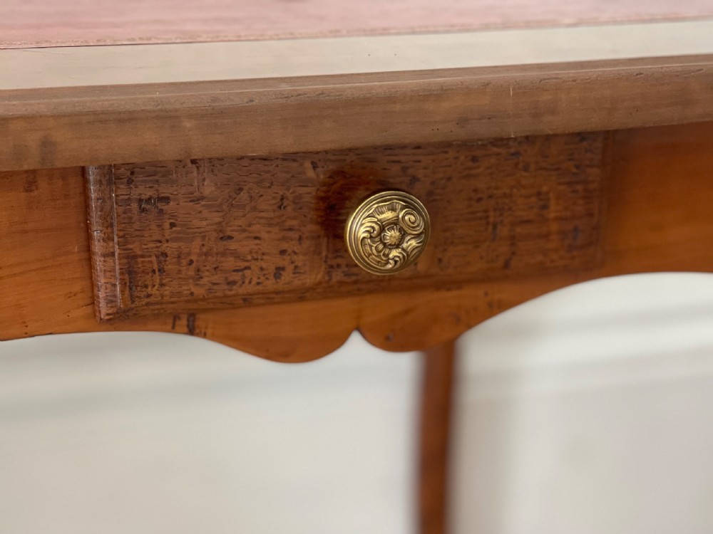 An antique French side table featuring a warm brown leather inset top, slender cabriole legs, and a single drawer with a brass knob. View VII