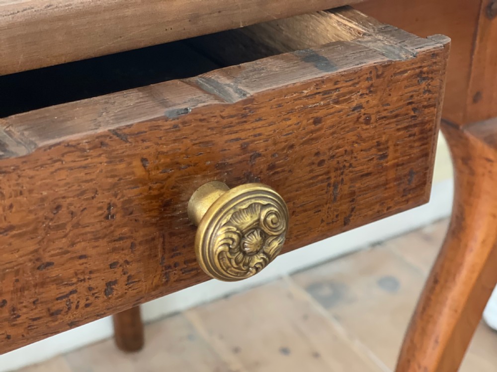 An antique French side table featuring a warm brown leather inset top, slender cabriole legs, and a single drawer with a brass knob. View IX