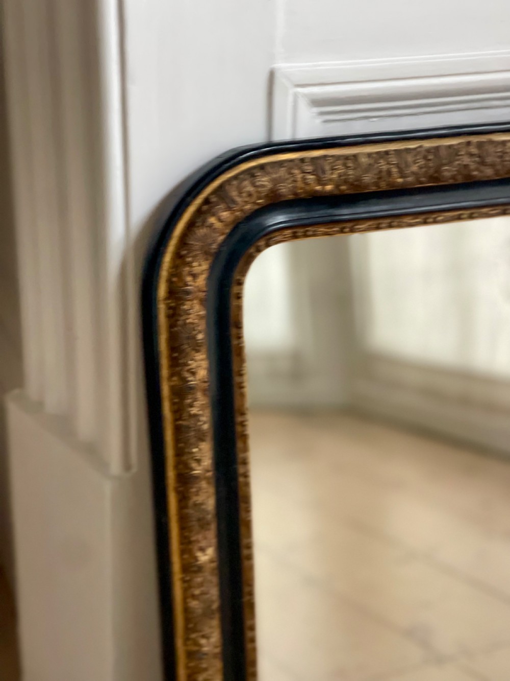 An arched antique French mirror featuring a dark painted outer border and a giltwood frame carved with foliate patterns. View III