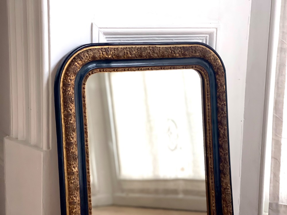 An arched antique French mirror featuring a dark painted outer border and a giltwood frame carved with foliate patterns. View IV