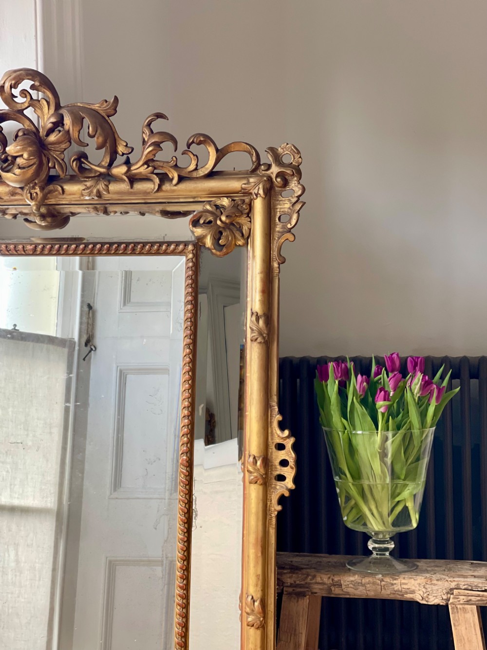 A large antique French giltwood wall mirror featuring carved acanthus cresting, corner flourishes, and bevelled mercury glass. View VIII