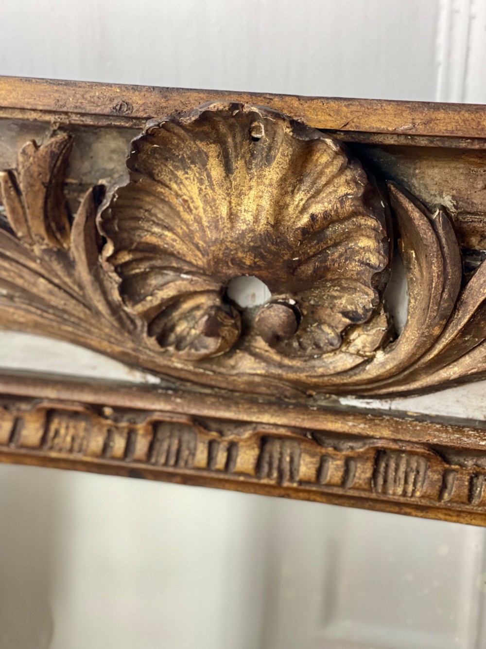 A tall rectangular antique French trumeau mirror featuring two glass panels within a painted cream frame with gilded carved mouldings and a shell crest. View V