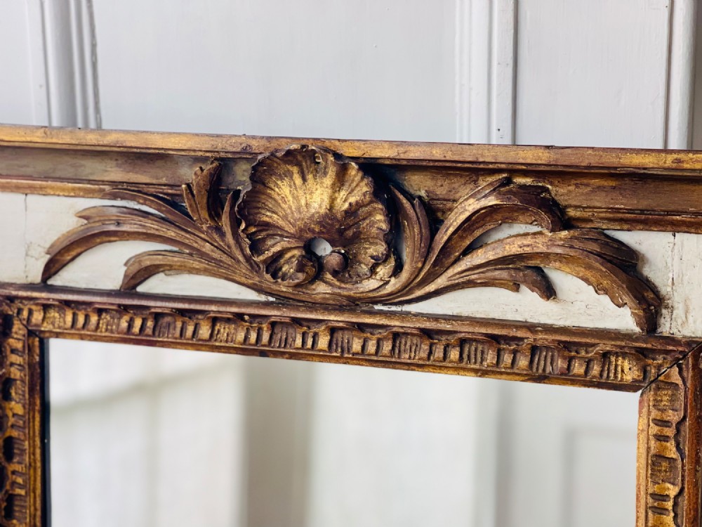 A tall rectangular antique French trumeau mirror featuring two glass panels within a painted cream frame with gilded carved mouldings and a shell crest. View VI