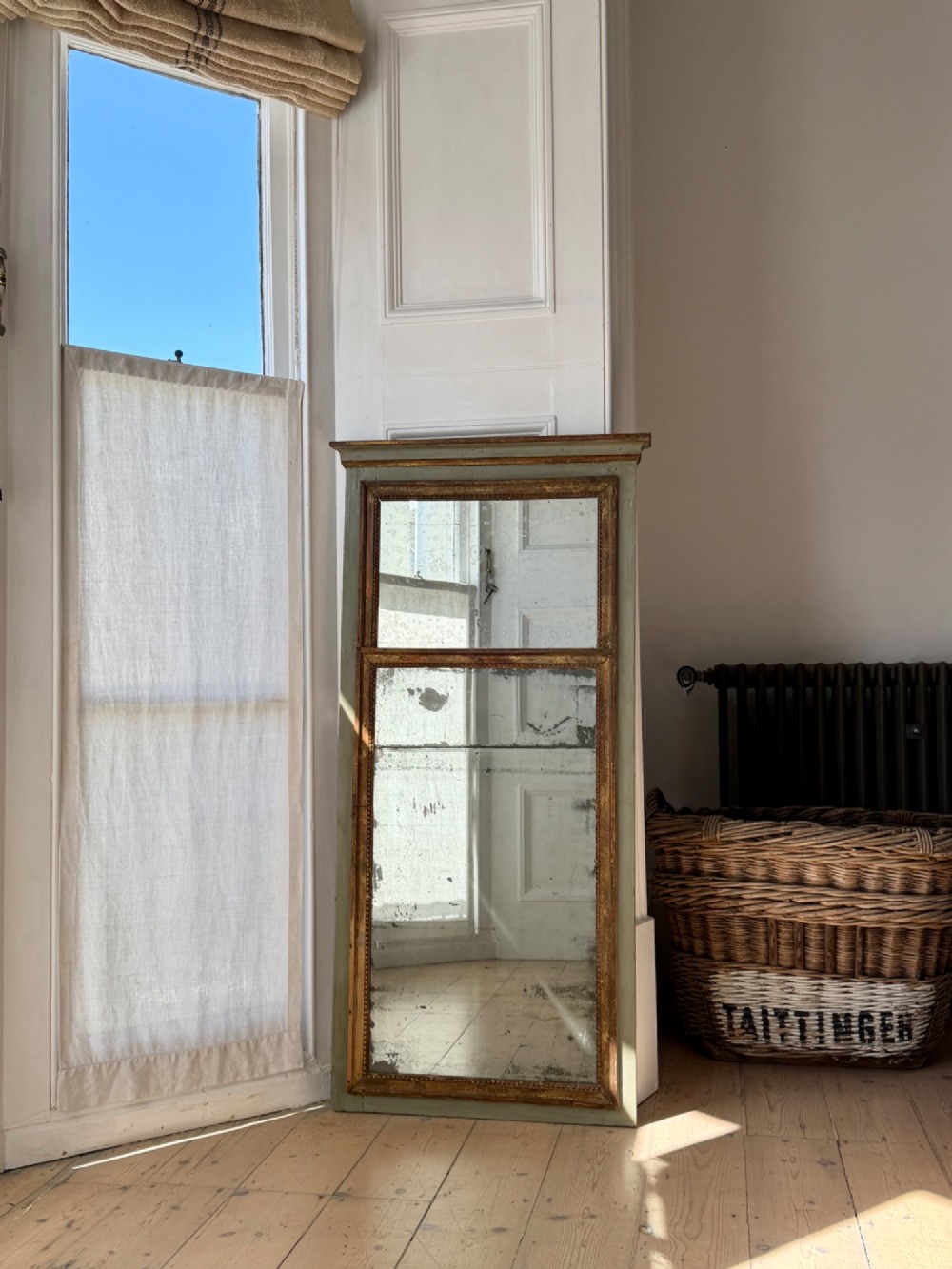 A tall rectangular French trumeau mirror featuring a sage green painted outer timber frame, a beaded gilt inner border, and two distressed mercury glass plates.