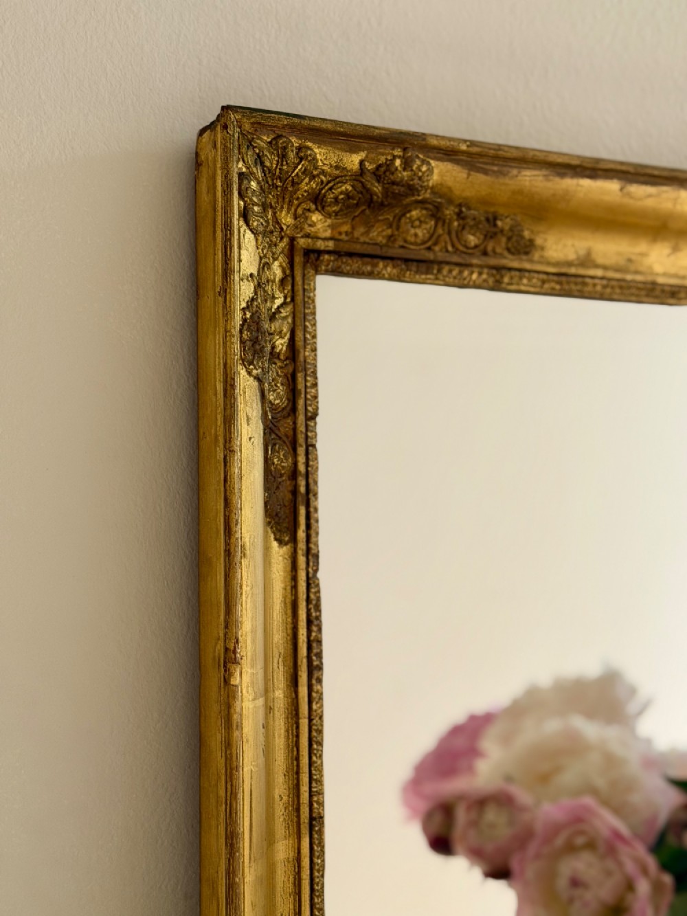 A rectangular antique French mirror framed in gold giltwood with ornate carved corner spandrels and subtle beaded borders. View II