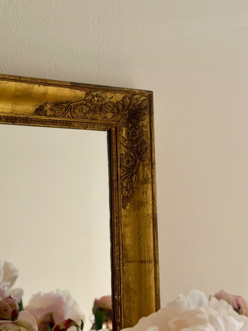 A rectangular antique French mirror framed in gold giltwood with ornate carved corner spandrels and subtle beaded borders. View III