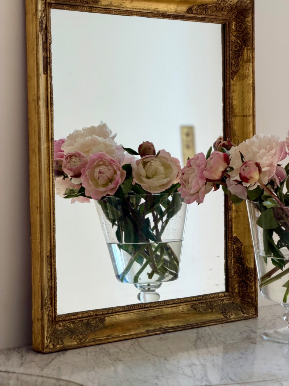 A rectangular antique French mirror framed in gold giltwood with ornate carved corner spandrels and subtle beaded borders. View V