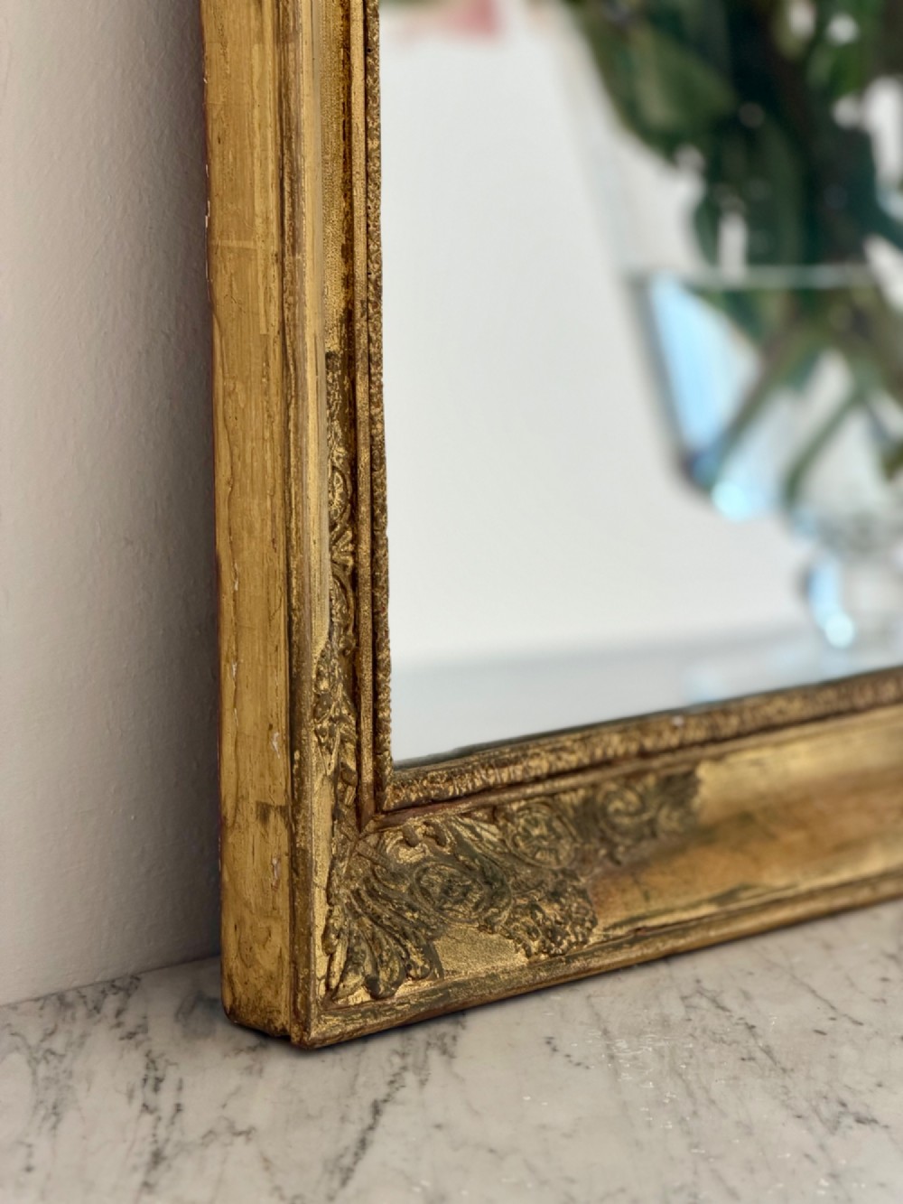 A rectangular antique French mirror framed in gold giltwood with ornate carved corner spandrels and subtle beaded borders. View VI
