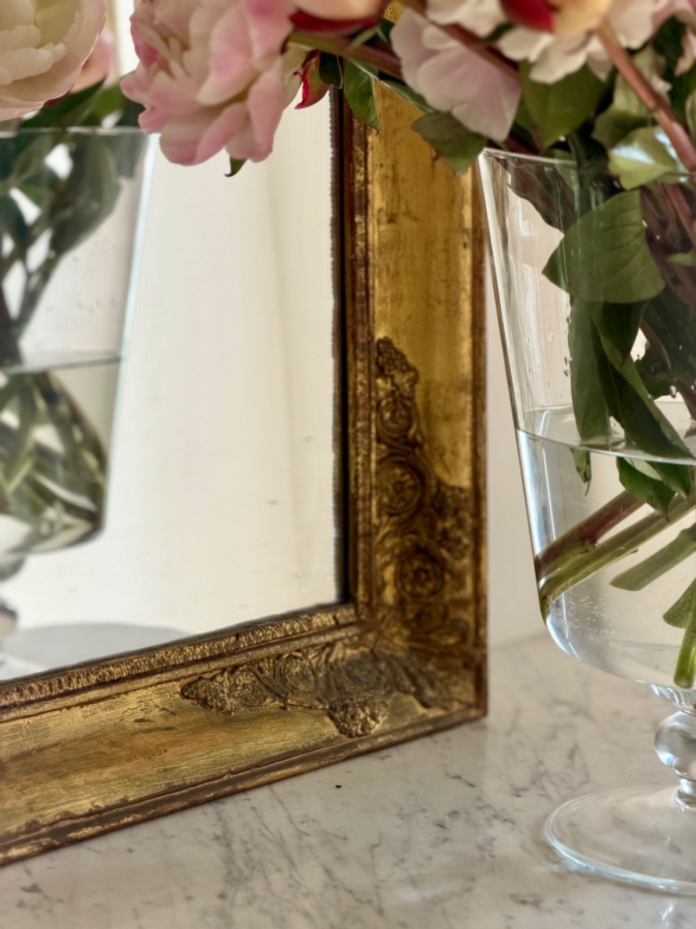 A rectangular antique French mirror framed in gold giltwood with ornate carved corner spandrels and subtle beaded borders. View VII