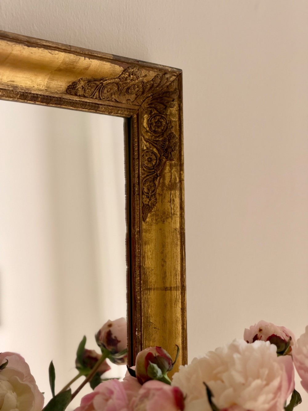A rectangular antique French mirror framed in gold giltwood with ornate carved corner spandrels and subtle beaded borders. View VIII