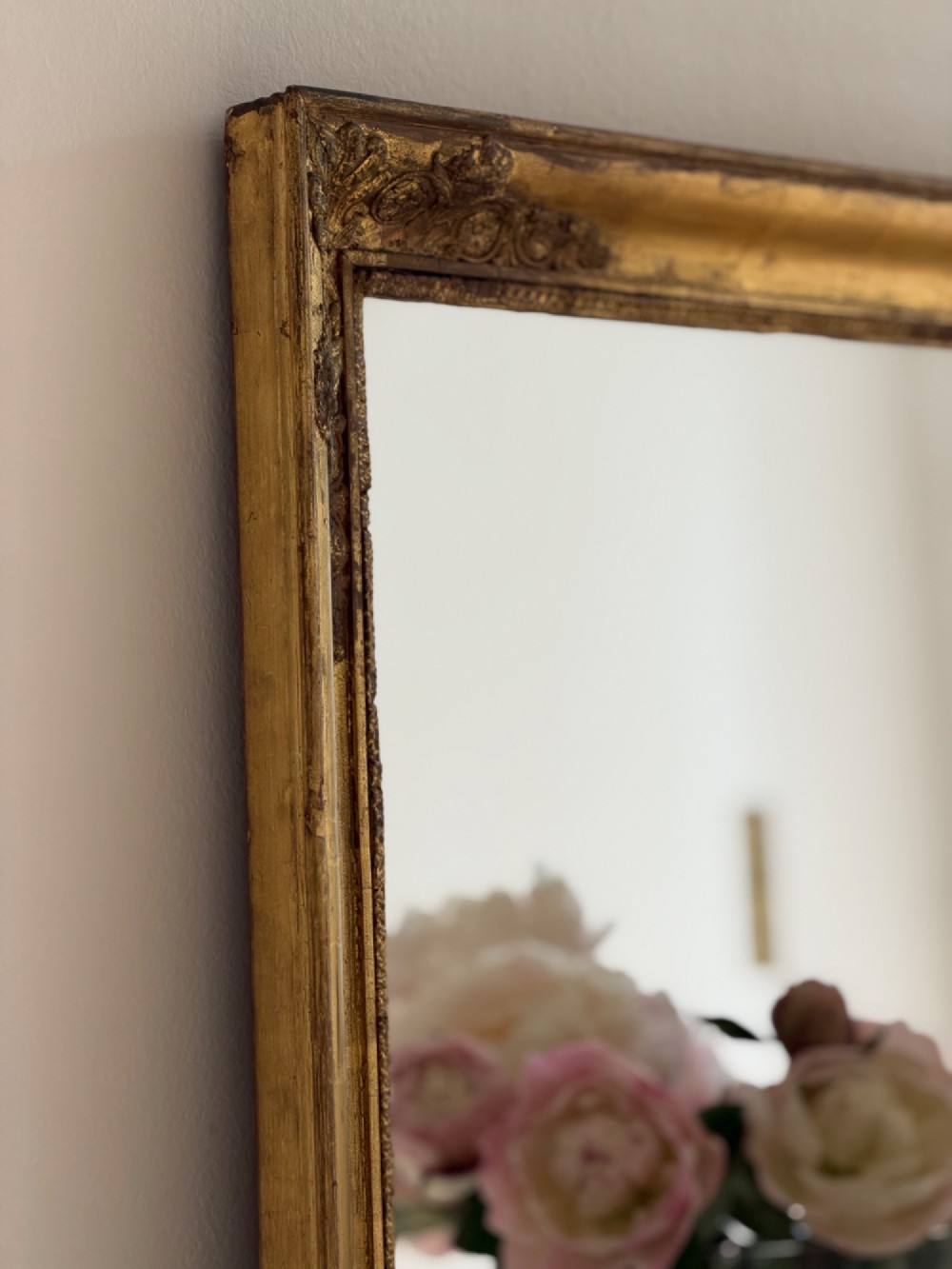 A rectangular antique French mirror framed in gold giltwood with ornate carved corner spandrels and subtle beaded borders. View IX