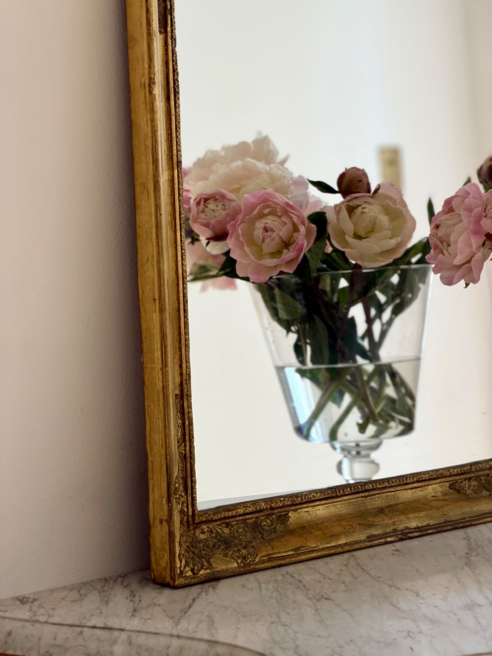 A rectangular antique French mirror framed in gold giltwood with ornate carved corner spandrels and subtle beaded borders. View XIII