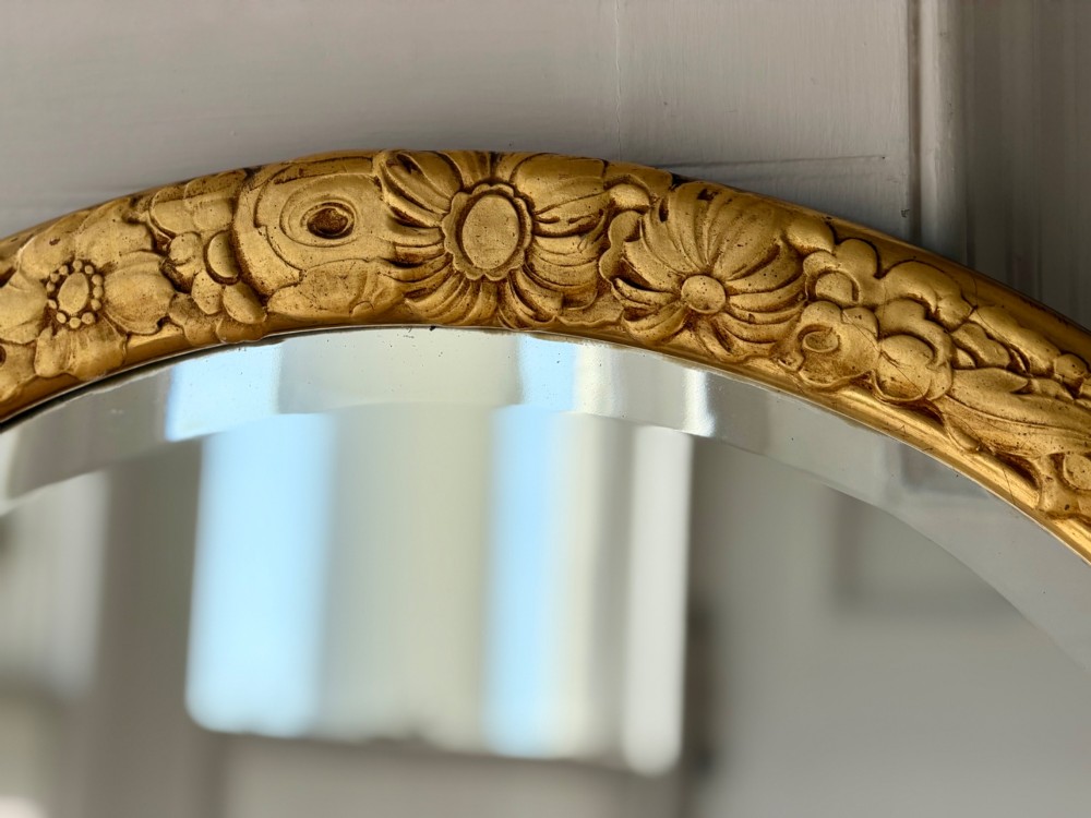 An arched tall mirror featuring a gilded gold frame with fluted side moulding and a carved floral crest. View VI