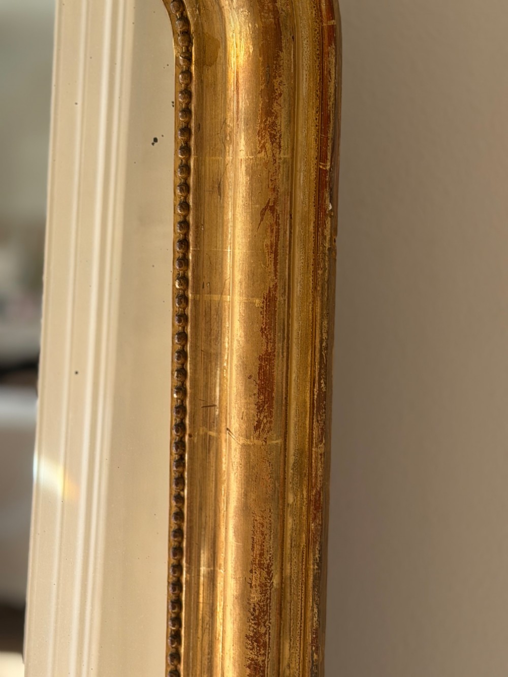 An antique French Louis Philippe wall mirror featuring a gilt frame with rounded upper corners, beaded inner border, and a carved crest. View VIII