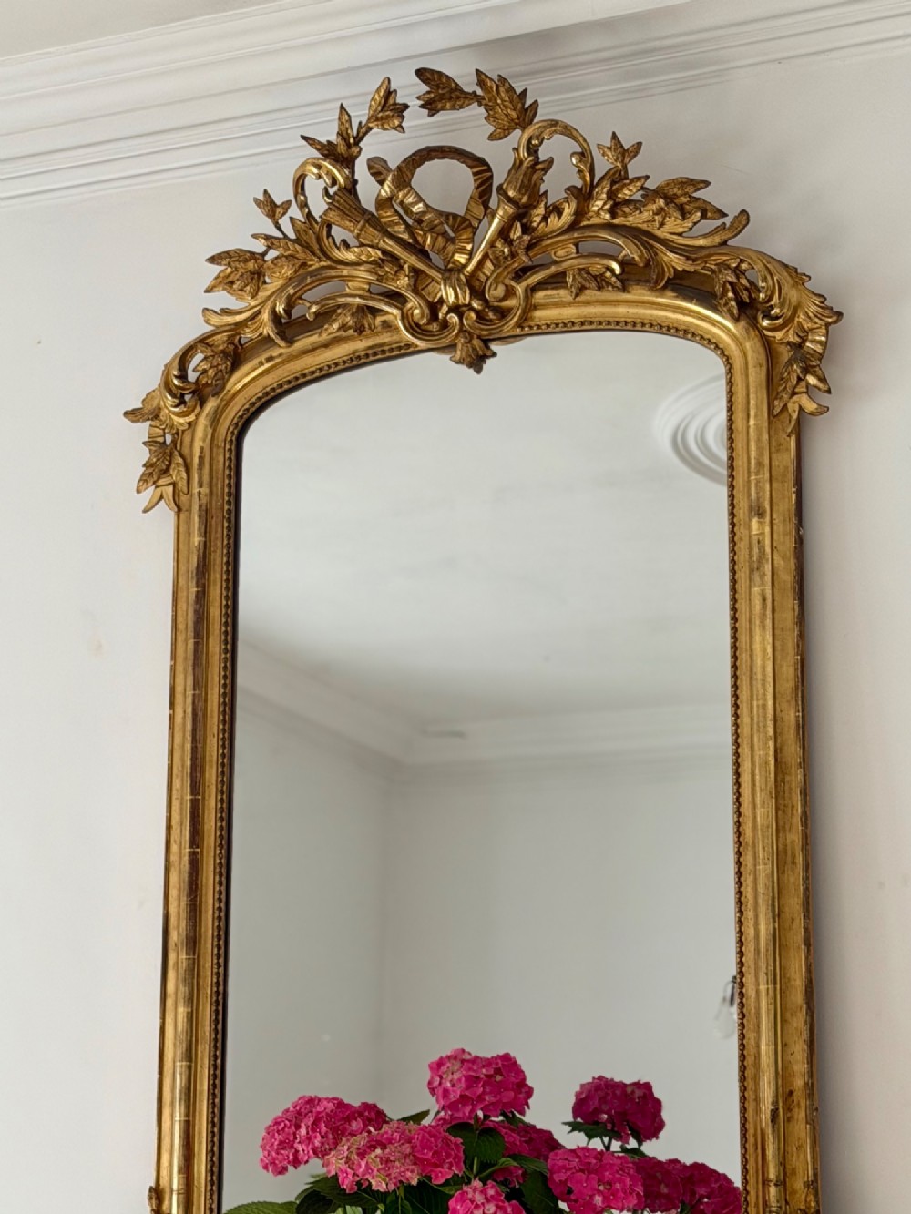 A tall antique French giltwood overmantel mirror featuring an arched frame topped with an ornate carved crest. View VIII
