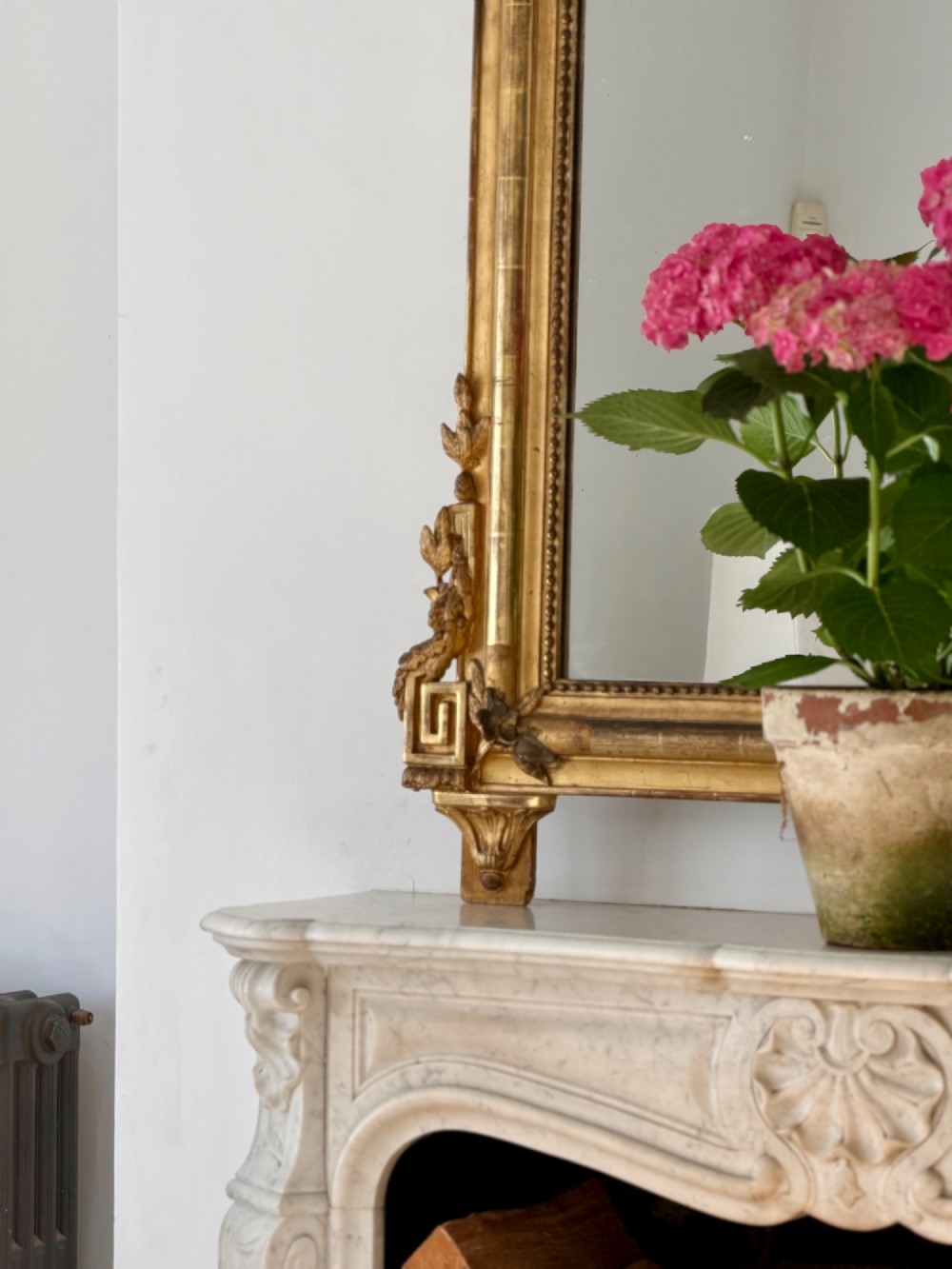 A tall antique French giltwood overmantel mirror featuring an arched frame topped with an ornate carved crest. View IX