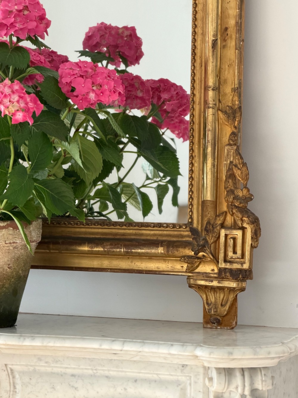 A tall antique French giltwood overmantel mirror featuring an arched frame topped with an ornate carved crest. View XII