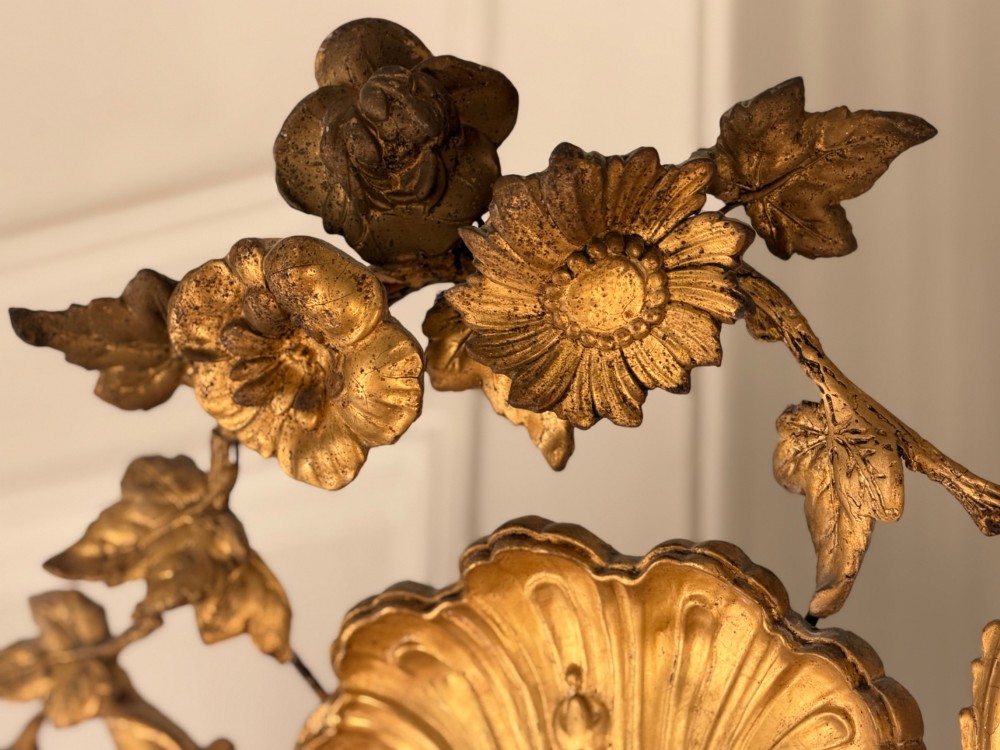 A large 18th century French giltwood mirror featuring an ornate floral shell crest and visible foxing on the mercury glass plate. View II
