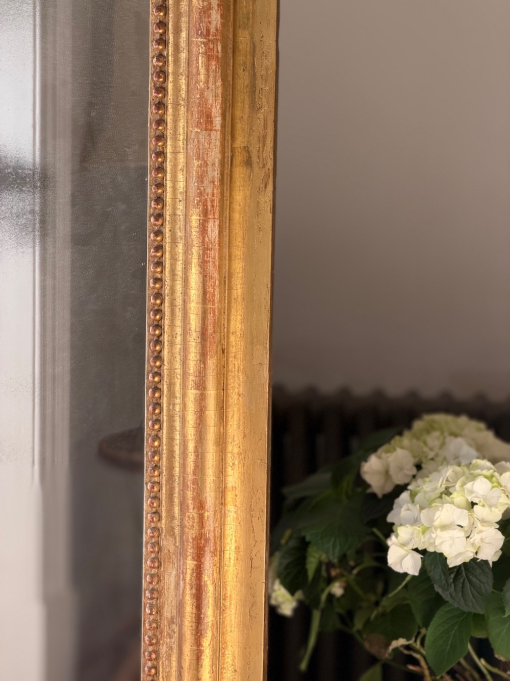A large 18th century French giltwood mirror featuring an ornate floral shell crest and visible foxing on the mercury glass plate. View VI