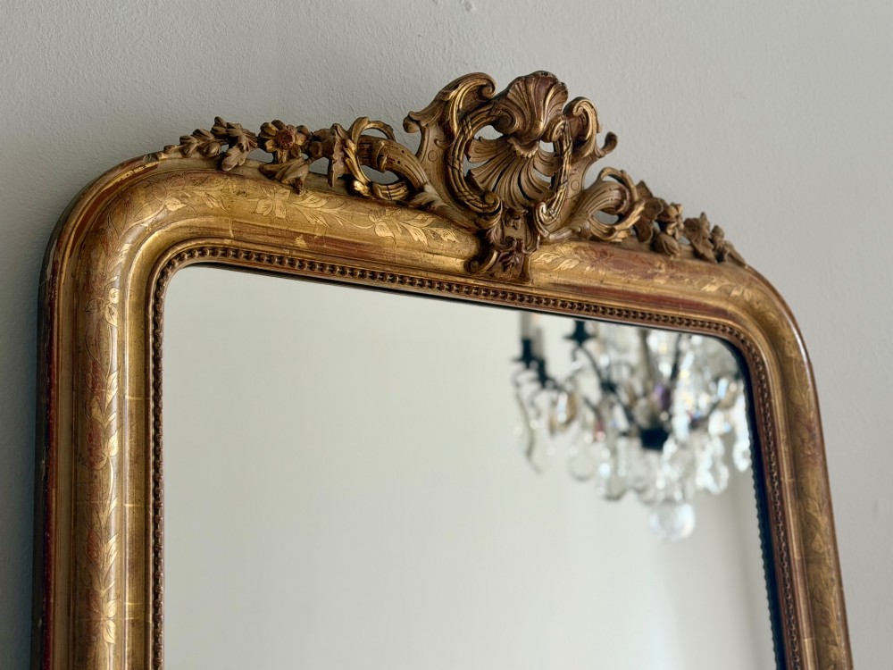 An antique French Louis Philippe giltwood mirror featuring a carved crest and incised floral frame detailing. View II