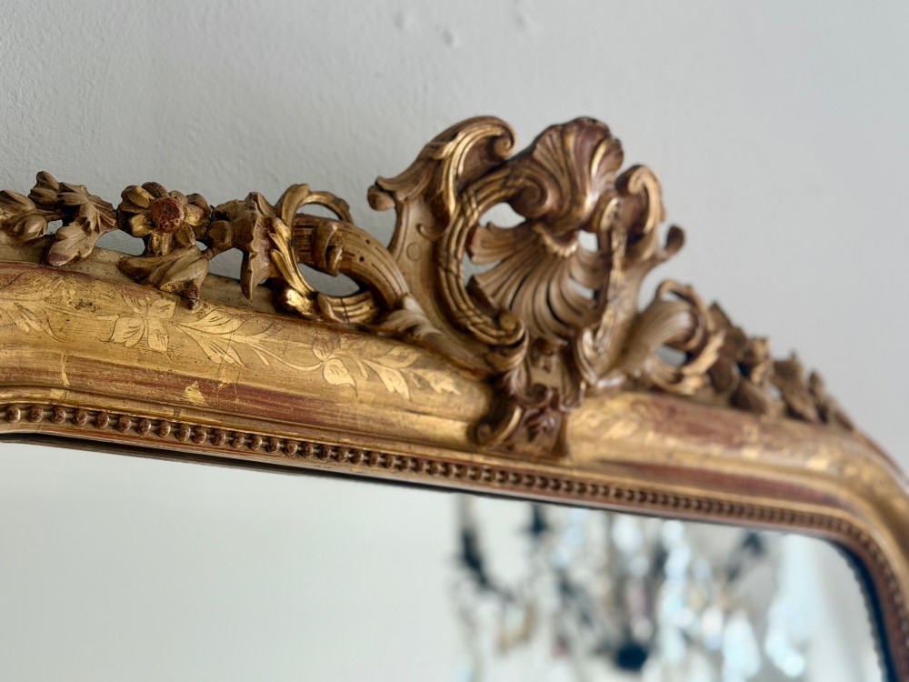 An antique French Louis Philippe giltwood mirror featuring a carved crest and incised floral frame detailing. View IV