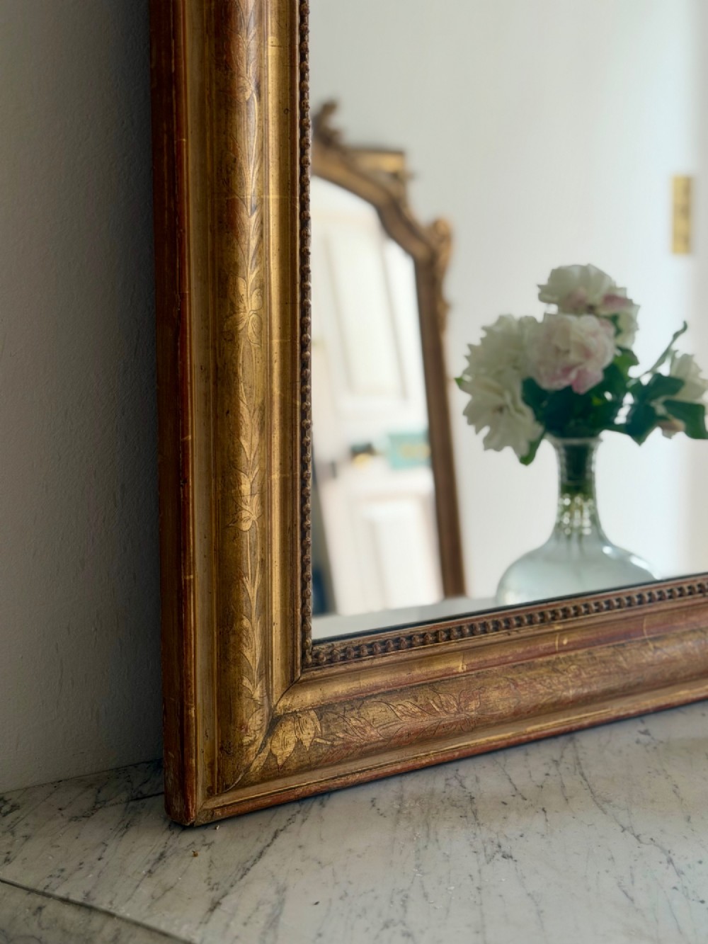 An antique French Louis Philippe giltwood mirror featuring a carved crest and incised floral frame detailing. View V