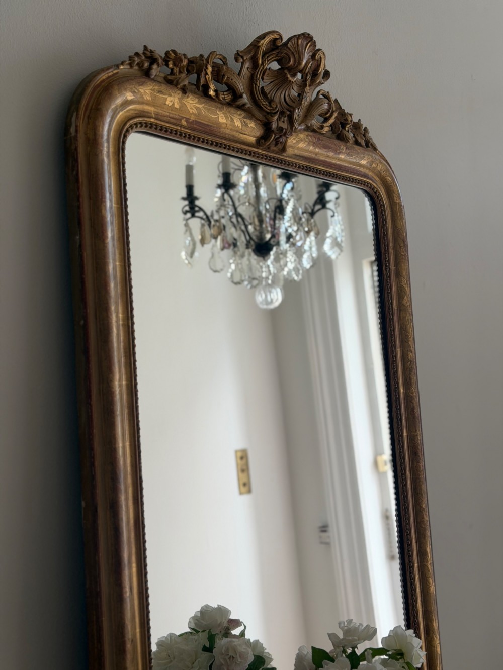 An antique French Louis Philippe giltwood mirror featuring a carved crest and incised floral frame detailing. View VIII