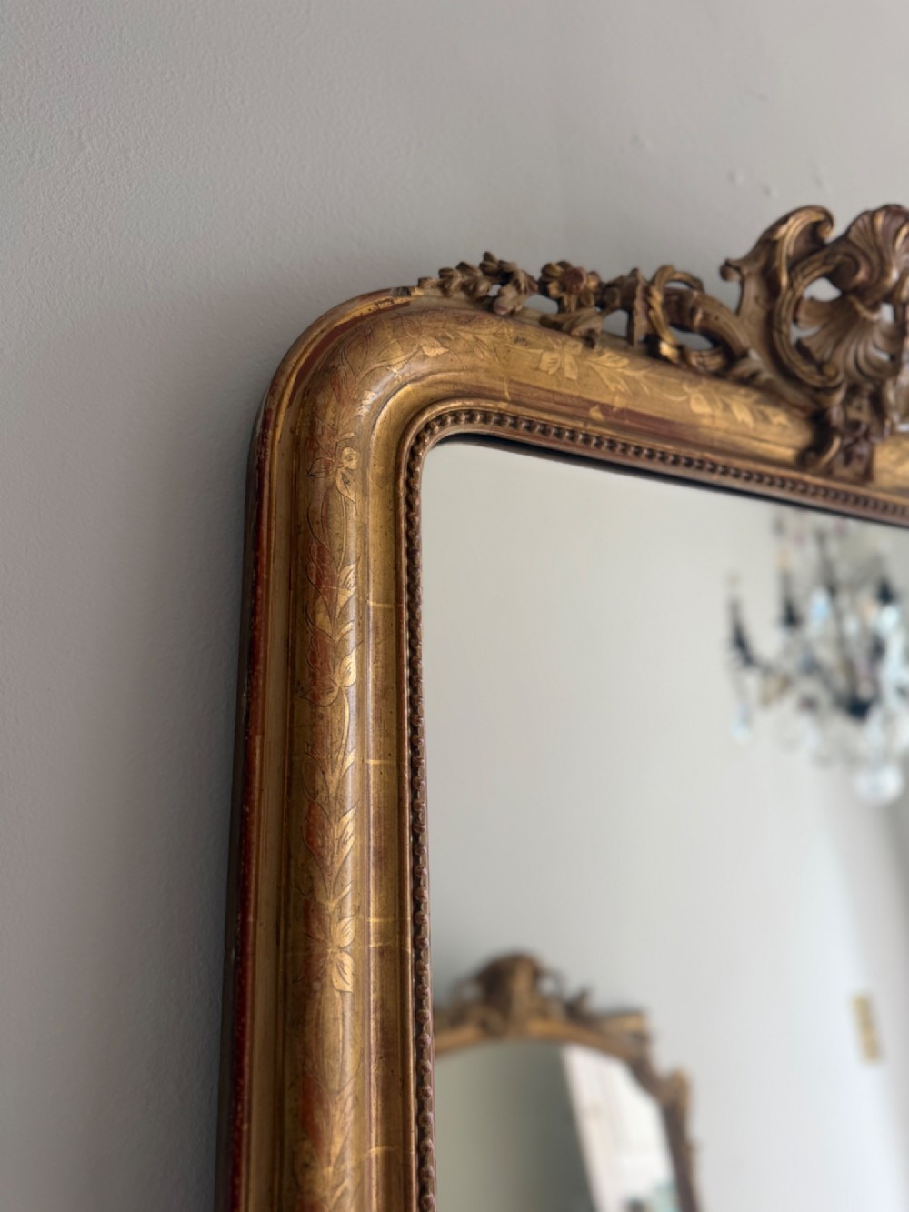 An antique French Louis Philippe giltwood mirror featuring a carved crest and incised floral frame detailing. View IX