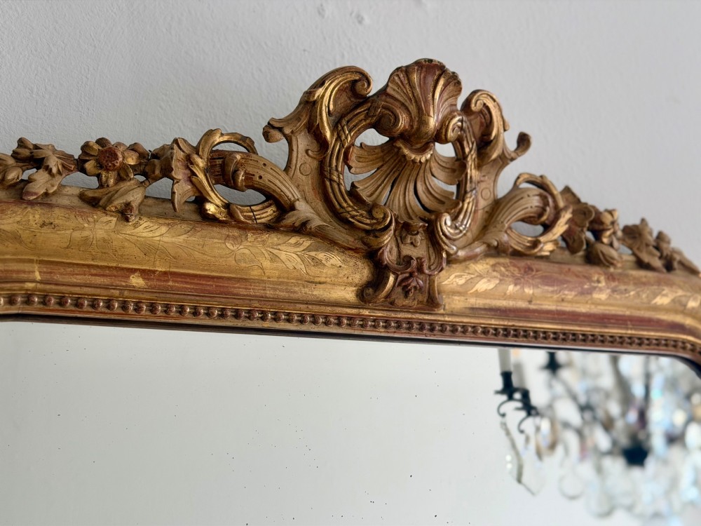 An antique French Louis Philippe giltwood mirror featuring a carved crest and incised floral frame detailing. View XI