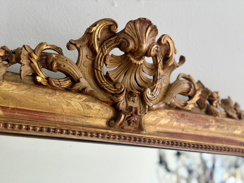An antique French Louis Philippe giltwood mirror featuring a carved crest and incised floral frame detailing. View XII